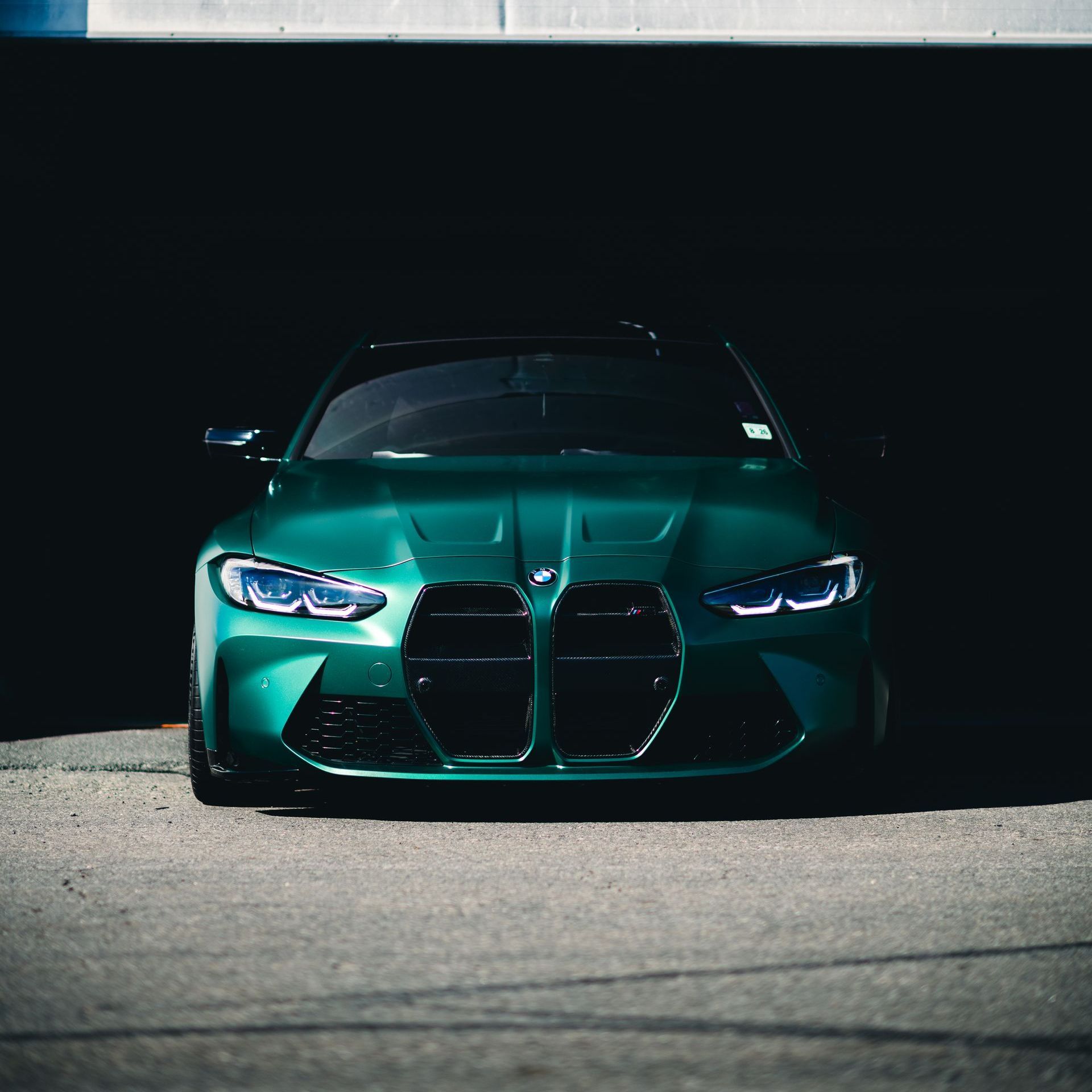 A green bmw m3 is parked in front of a building
