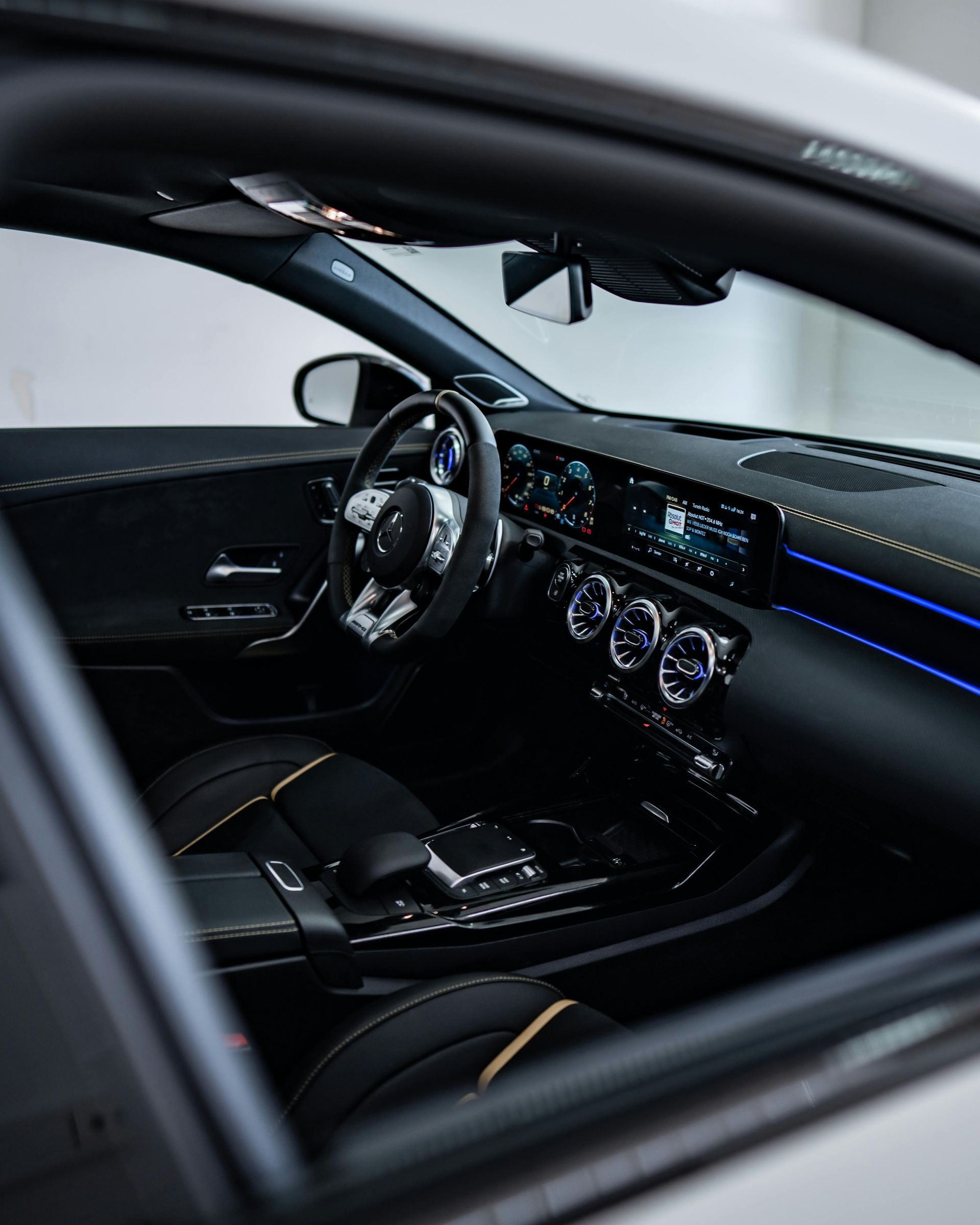 Black interior of a Mercedes-Benz car: dashboard, steering wheel, and seats visible.