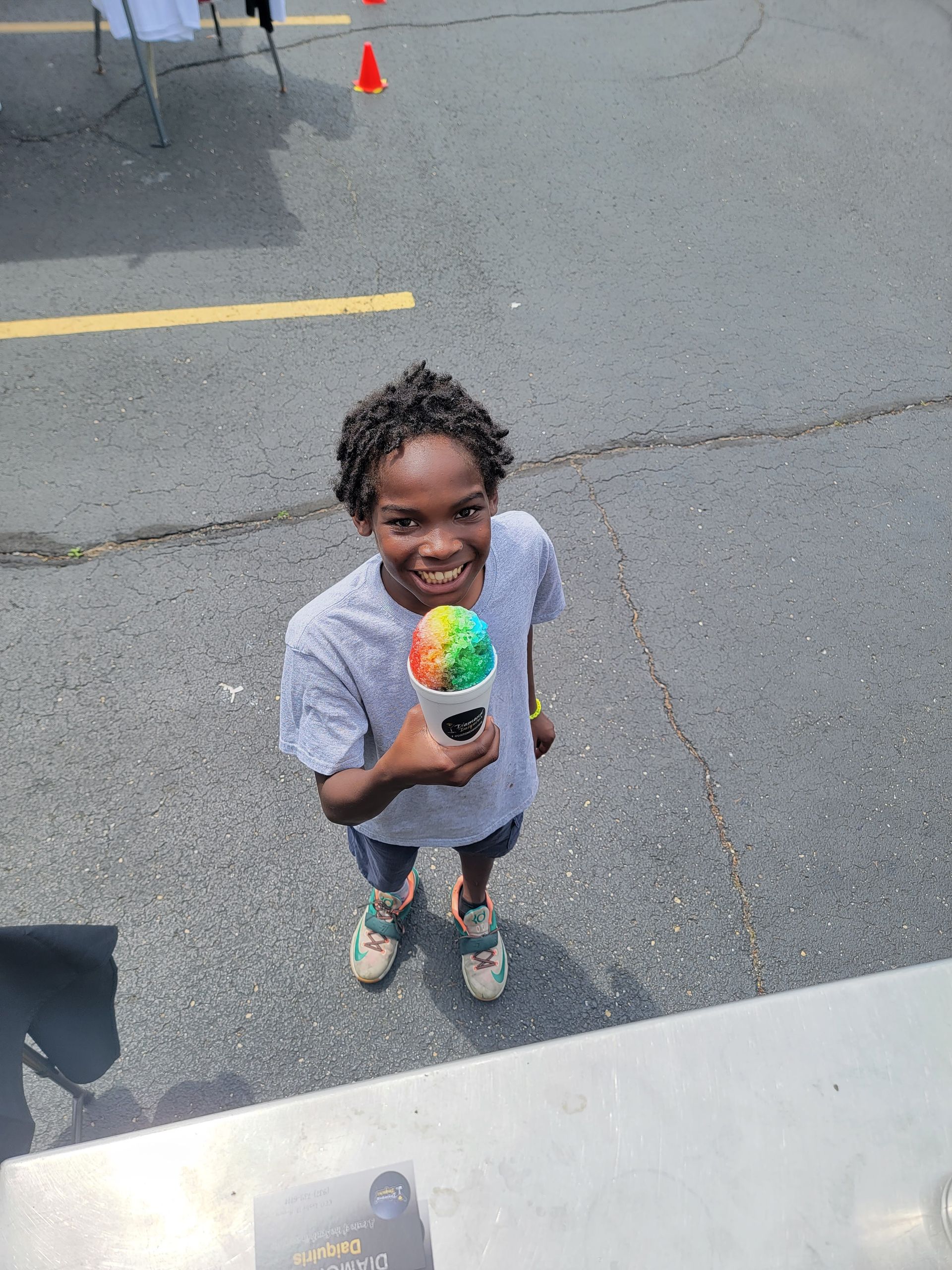 A young boy is holding a cup of ice cream and smiling.