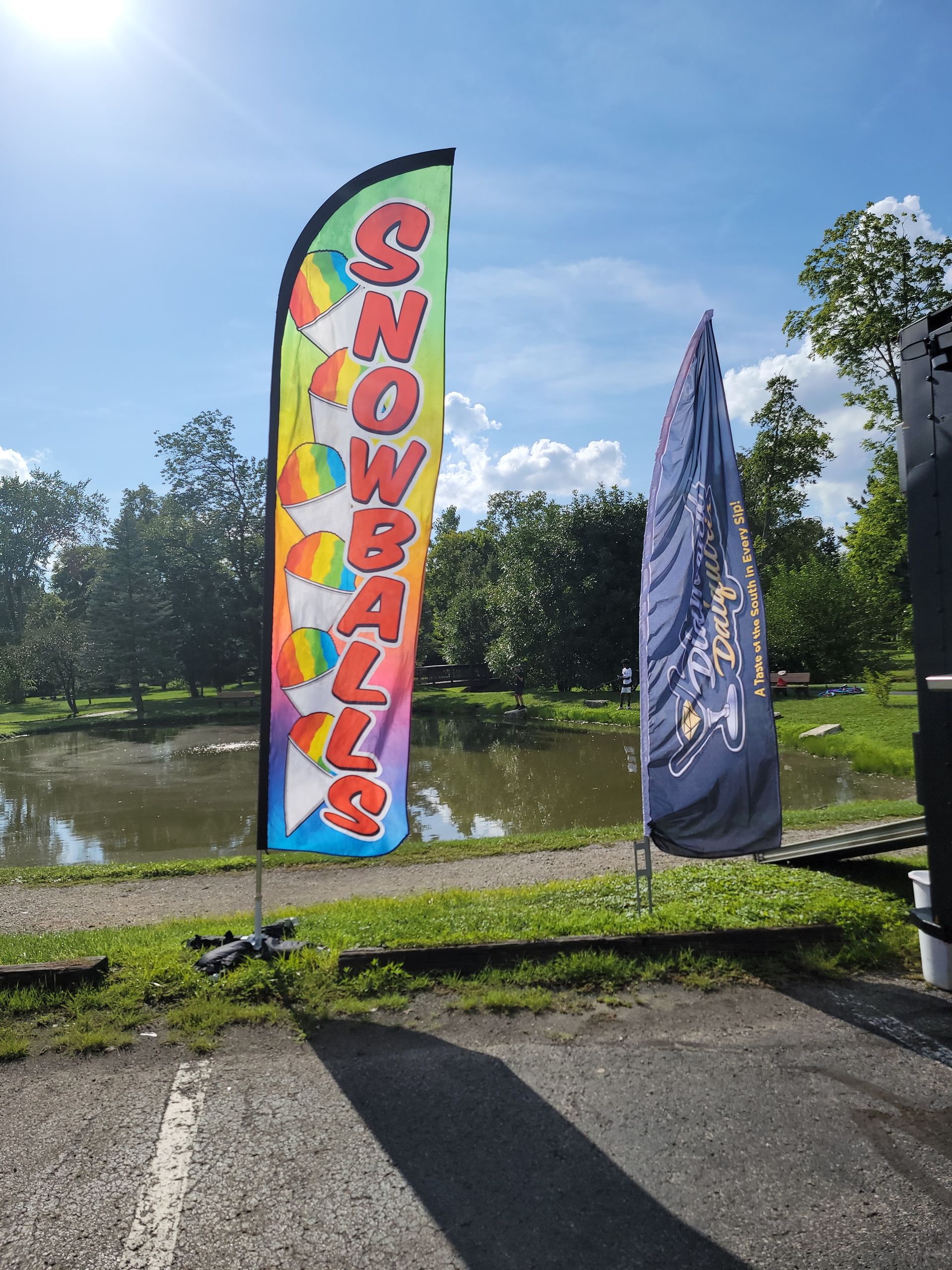 A colorful flag that says snowballs is in a parking lot