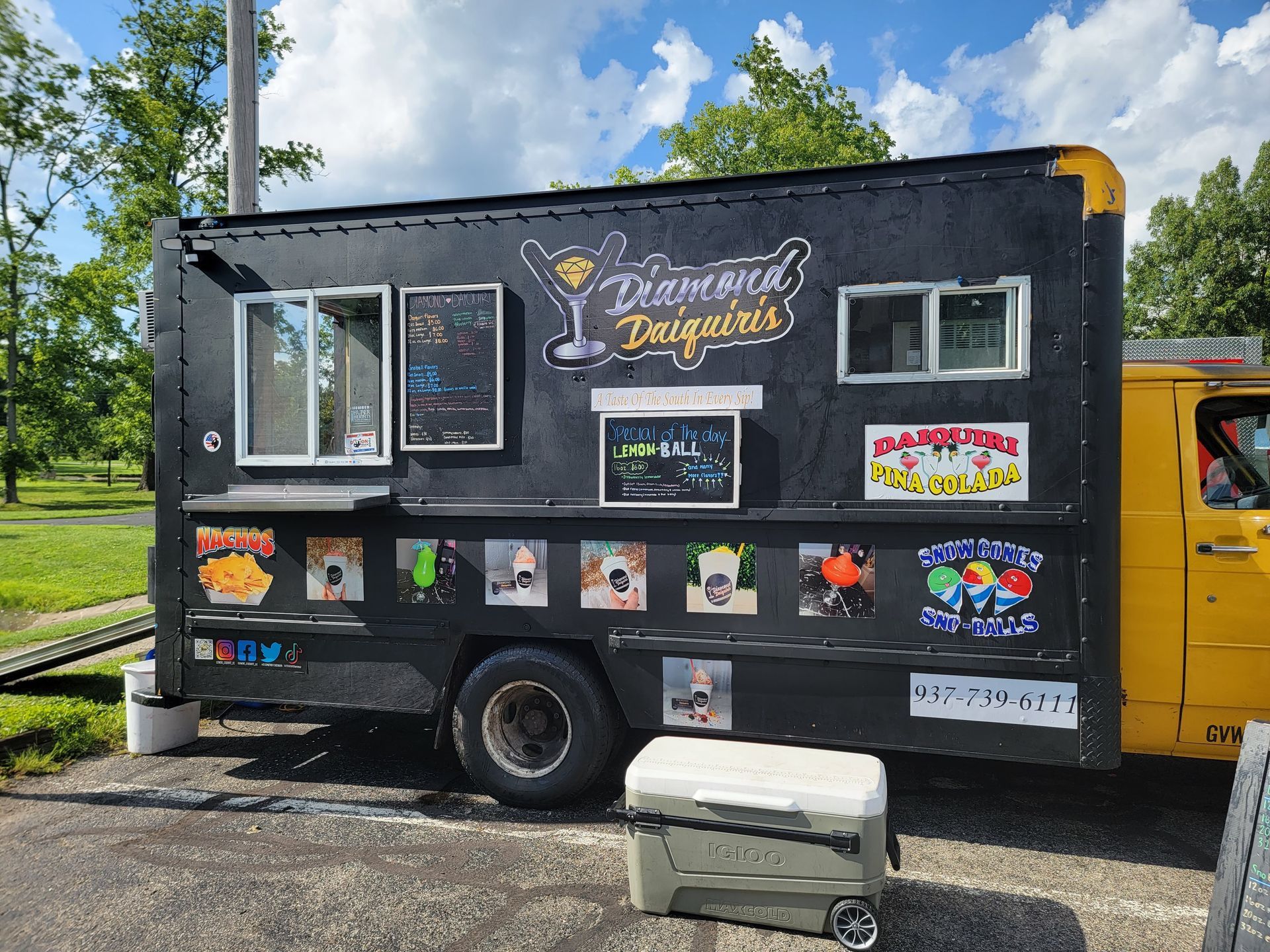 A black and yellow food truck is parked in a parking lot.