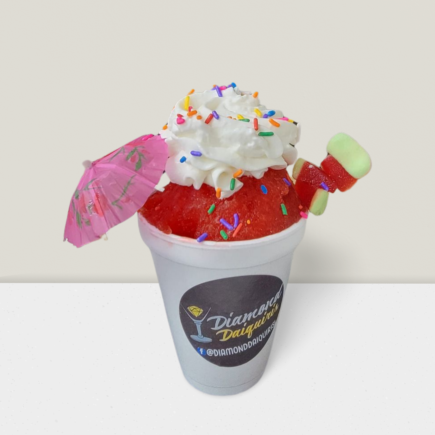 A cup of watermelon ice cream with whipped cream and sprinkles