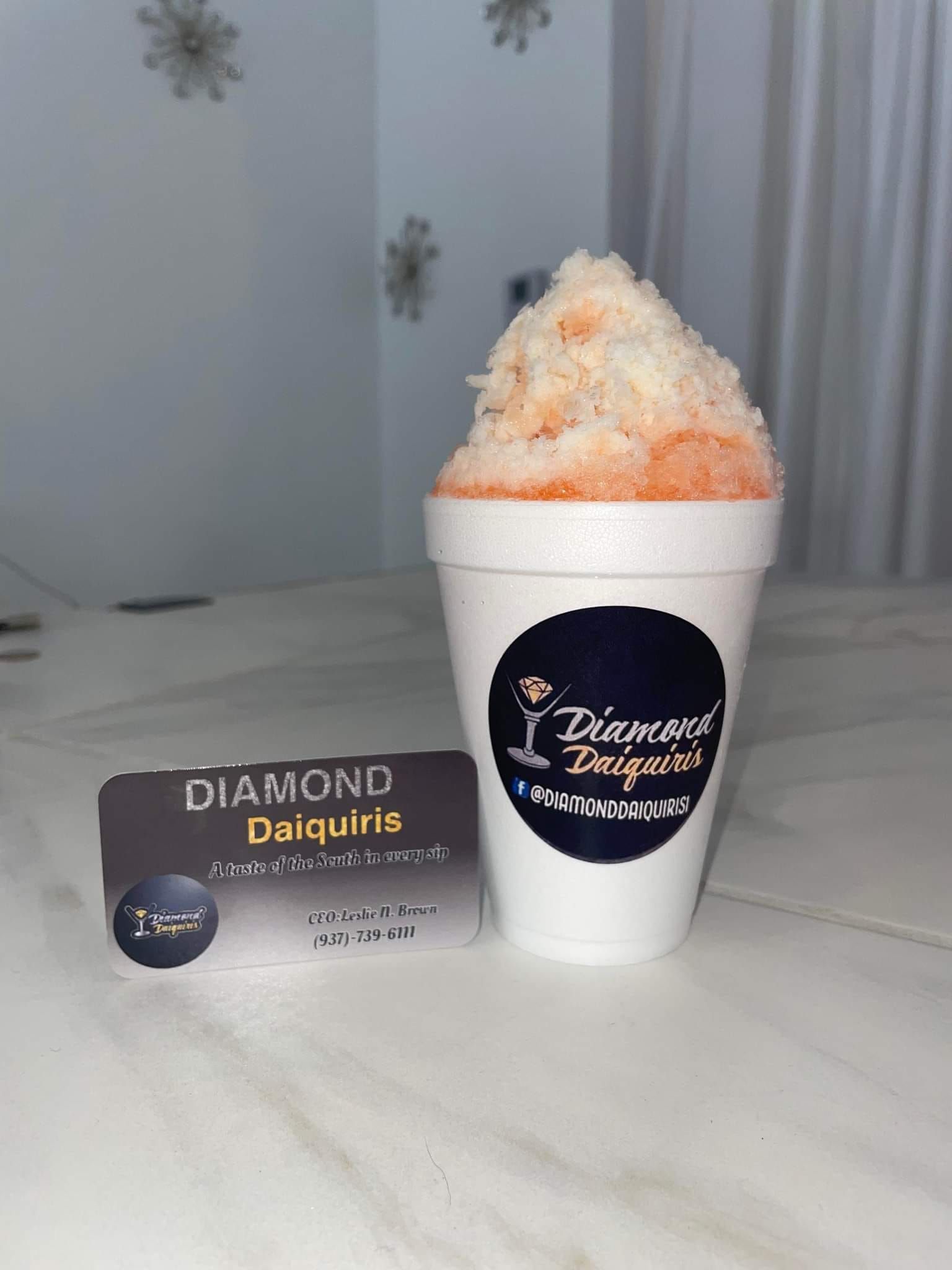 A cup of shaved ice is sitting on a table next to a business card.