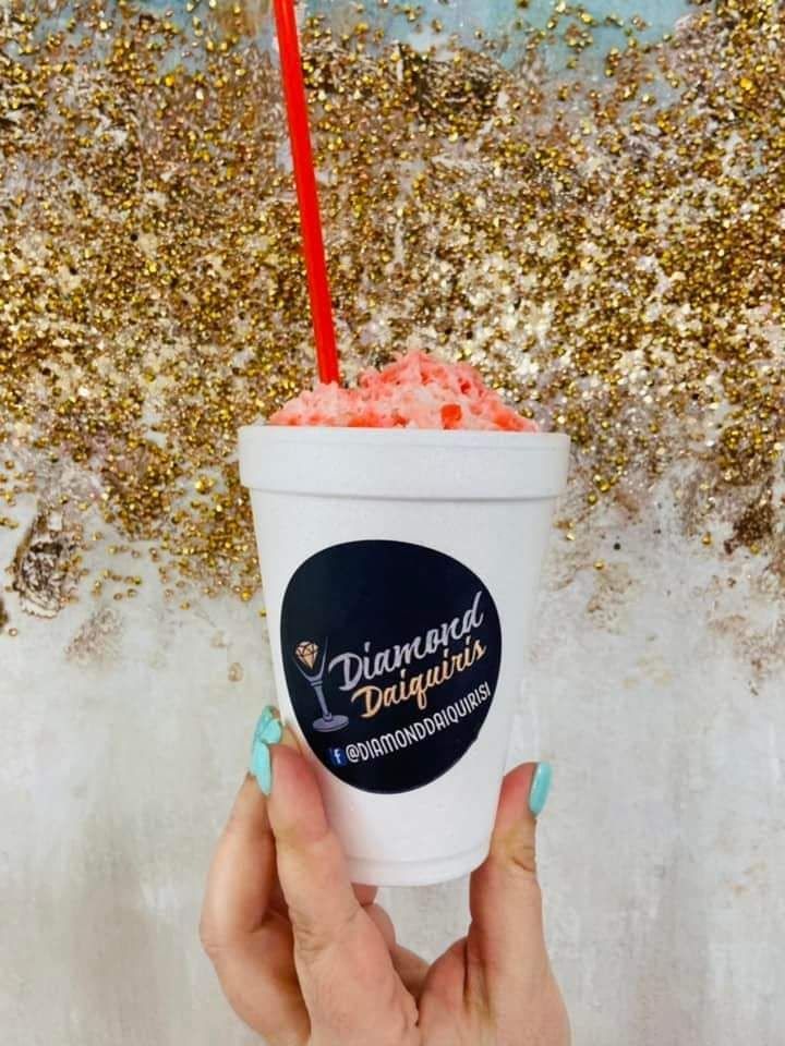 A person is holding a cup of ice cream with a red straw.