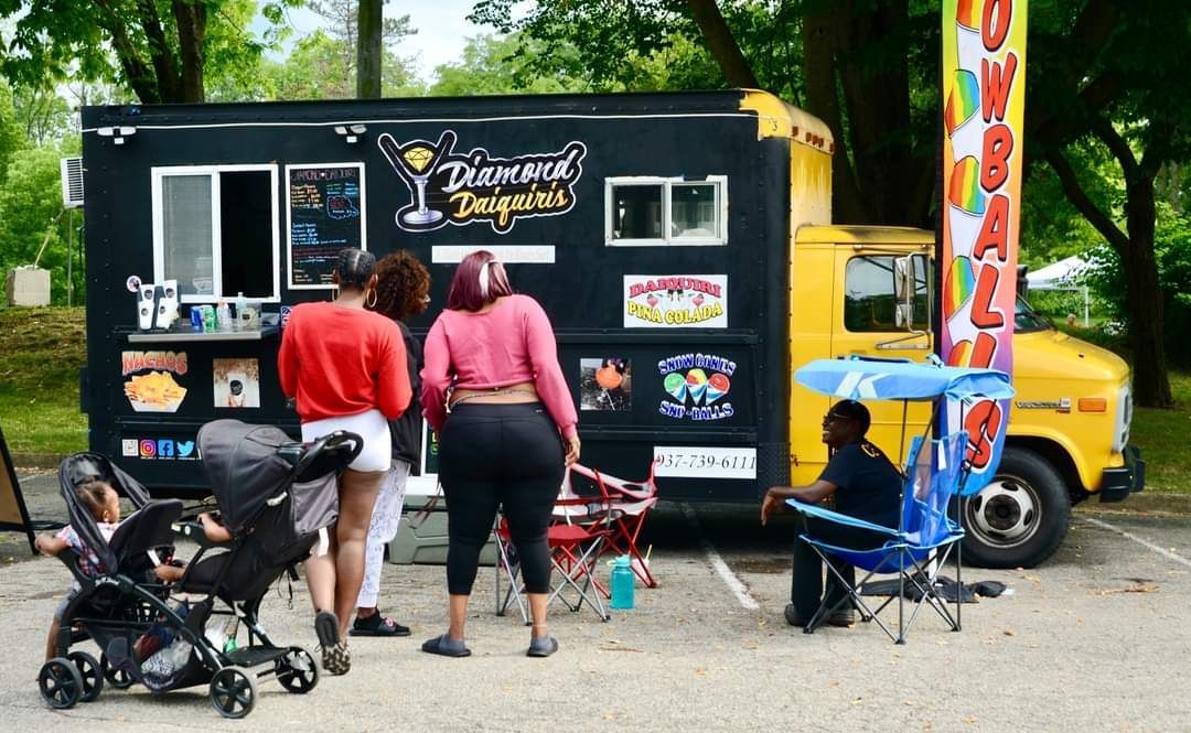 A group of people are standing in front of a food truck.