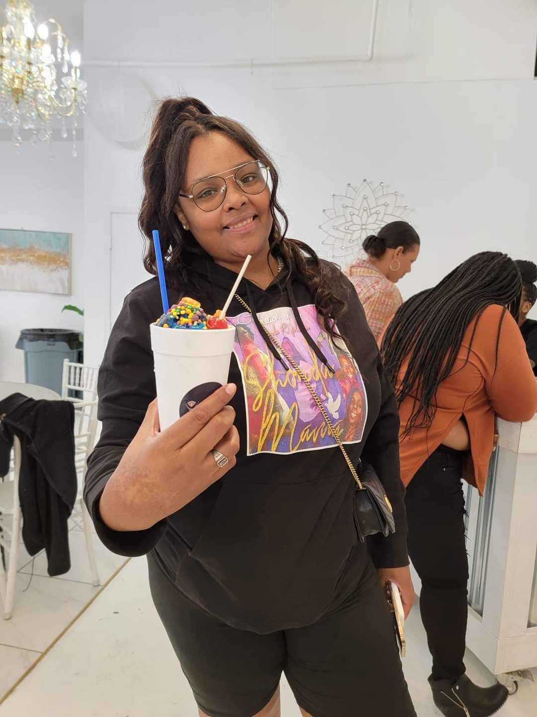 A woman is holding a cup of ice cream with a straw.