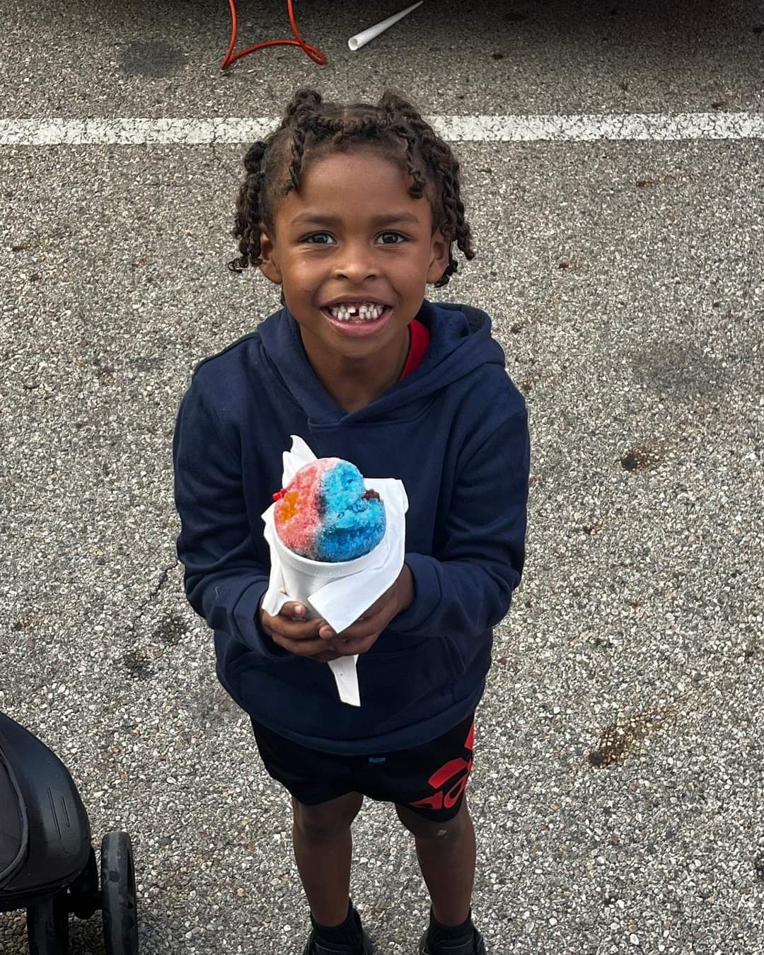 A young boy is holding a cone of ice cream and smiling.