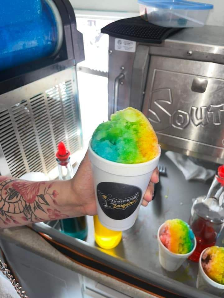 A person holding a cup of shaved ice in front of a machine that says sour