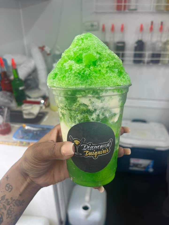 A person is holding a cup of green shaved ice.