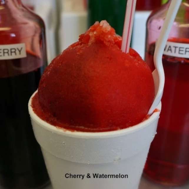 A cup of cherry and watermelon ice cream with a straw