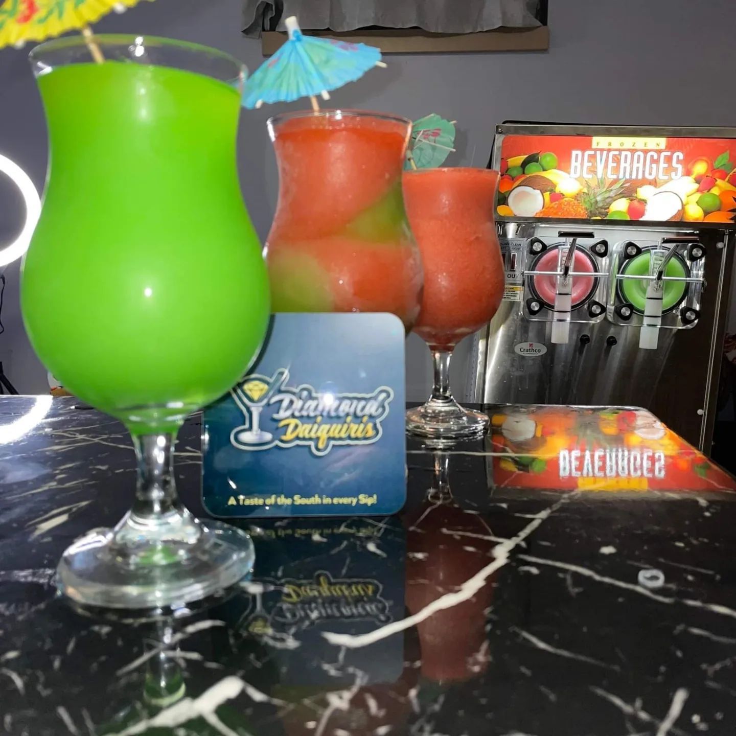 Two glasses of drinks are on a table next to a machine that says beverages