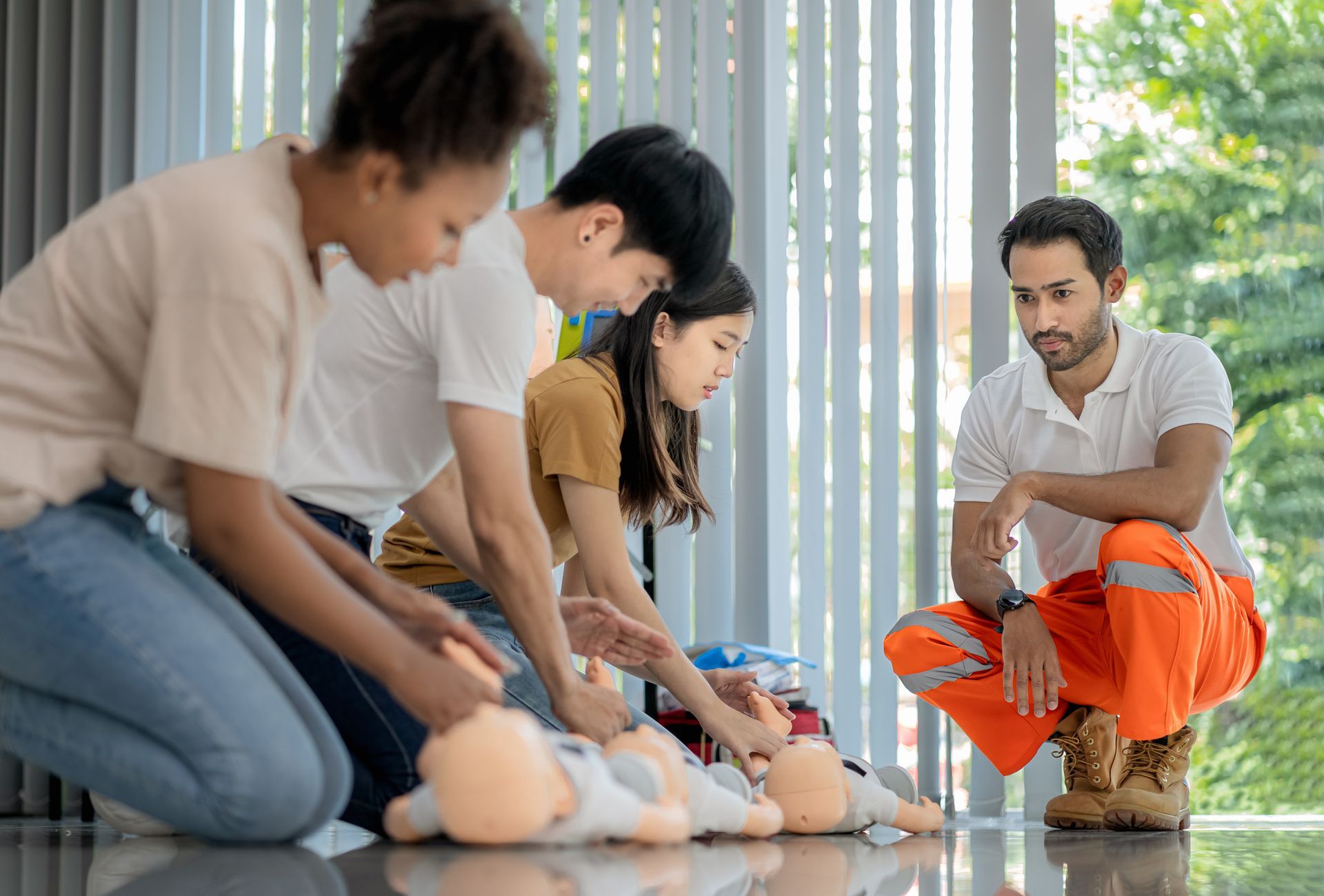 A person wearing blue gloves is holding a baby mannequin.
