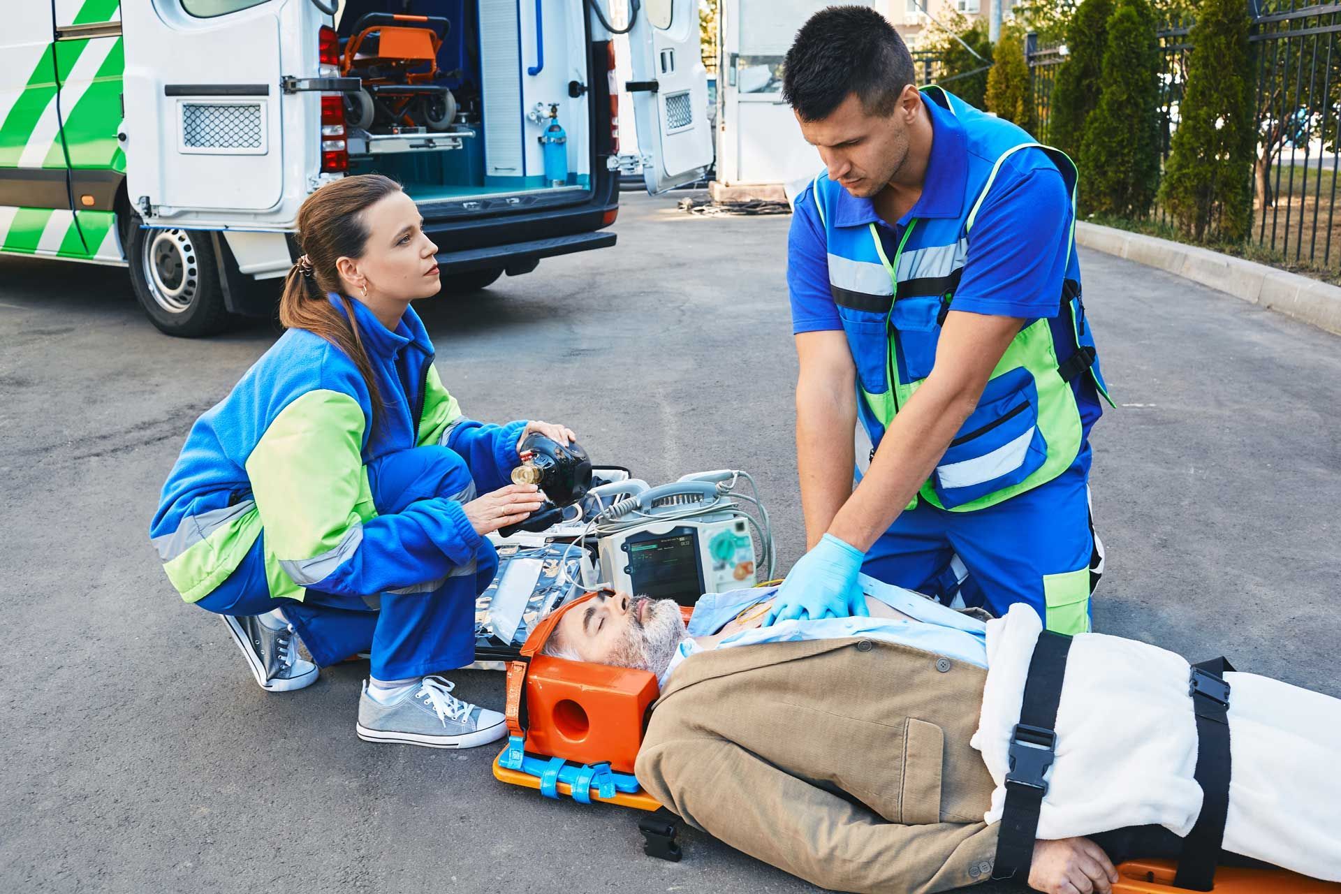 A man is laying on a stretcher with an ambulance in the background.