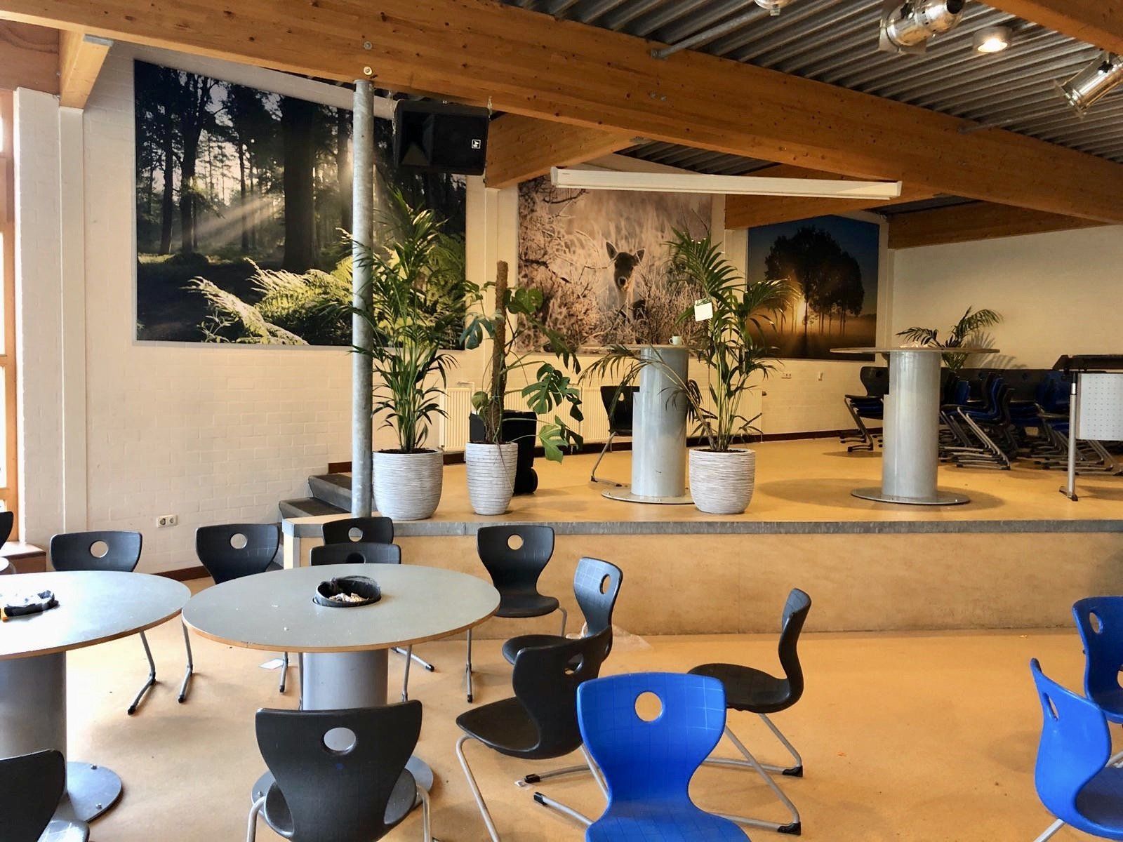 Interieur van een ruimte met podium en tafels. Natuurfoto's als wanddecoratie.
