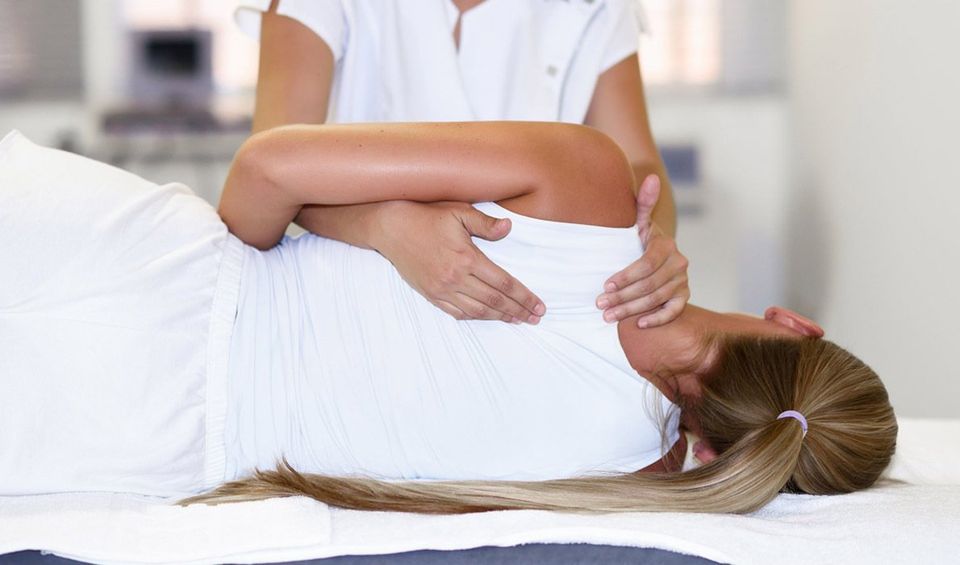 Female Physiotherapist Giving Shoulder Massage —
