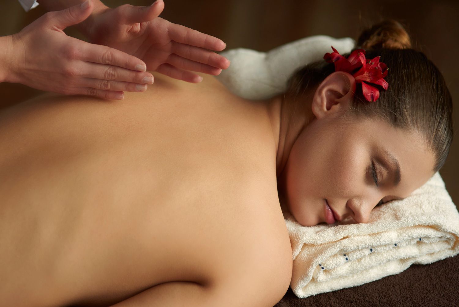 A woman is getting a massage at a spa with a flower in her hair.