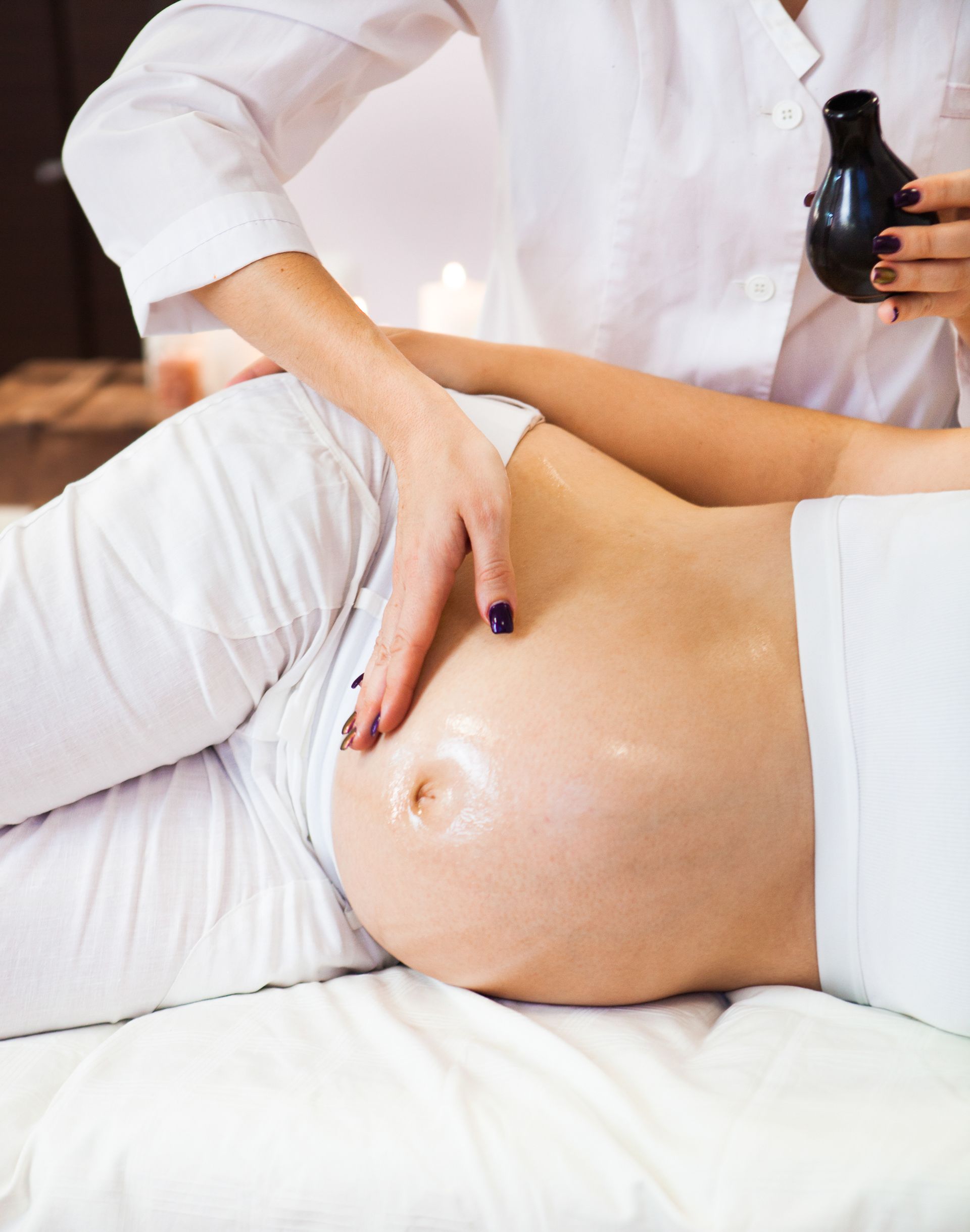 A pregnant woman is getting a massage at a spa.