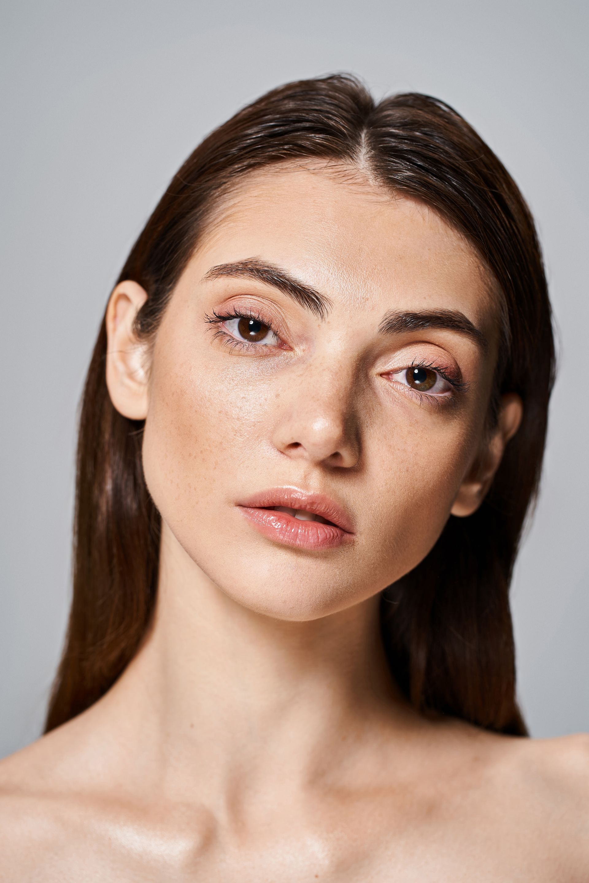 A close up of a woman 's face with a gray background.