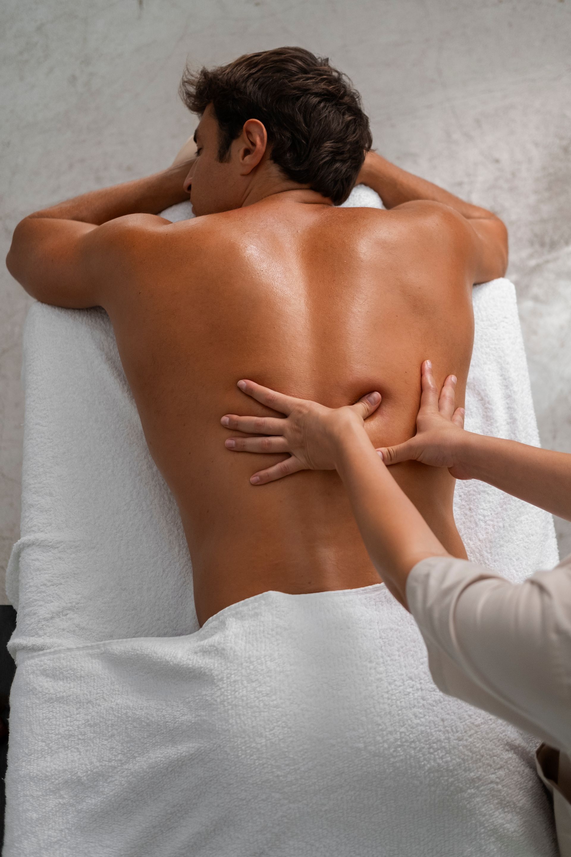 A man is laying on a bed getting a massage.