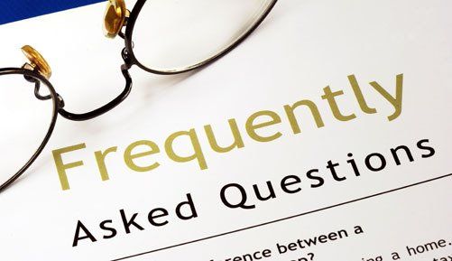 Paper saying Frequently Asked Questions and a pair of glasses