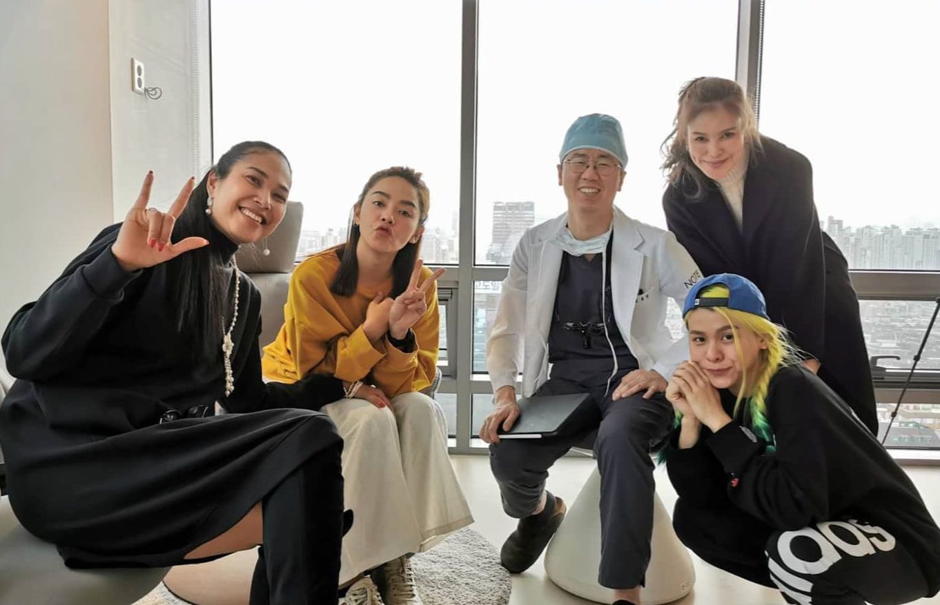 Group of people with a doctor in a well-lit room. They are smiling, making hand gestures.