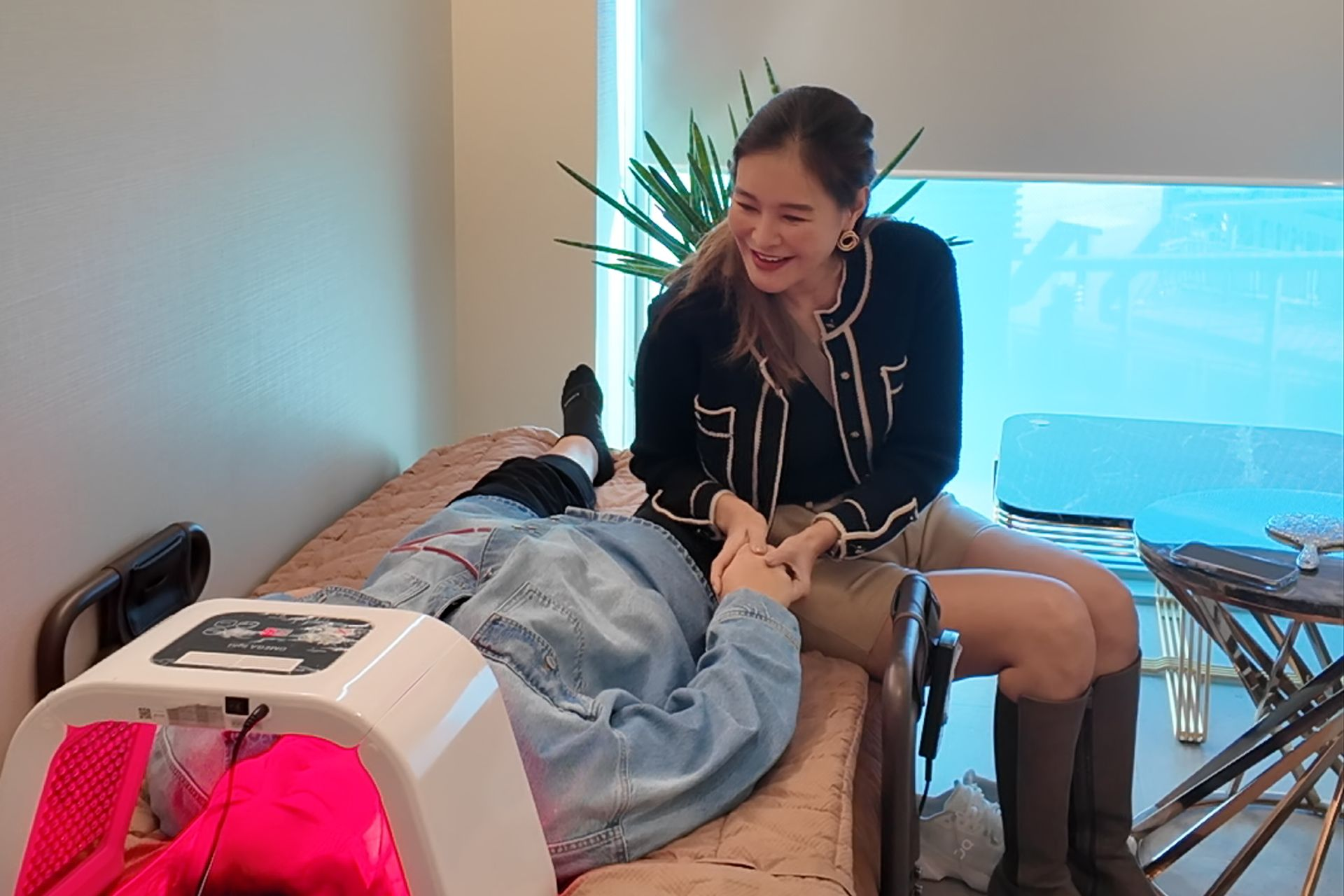 Woman assisting a person undergoing light therapy treatment. Smiling, indoors.
