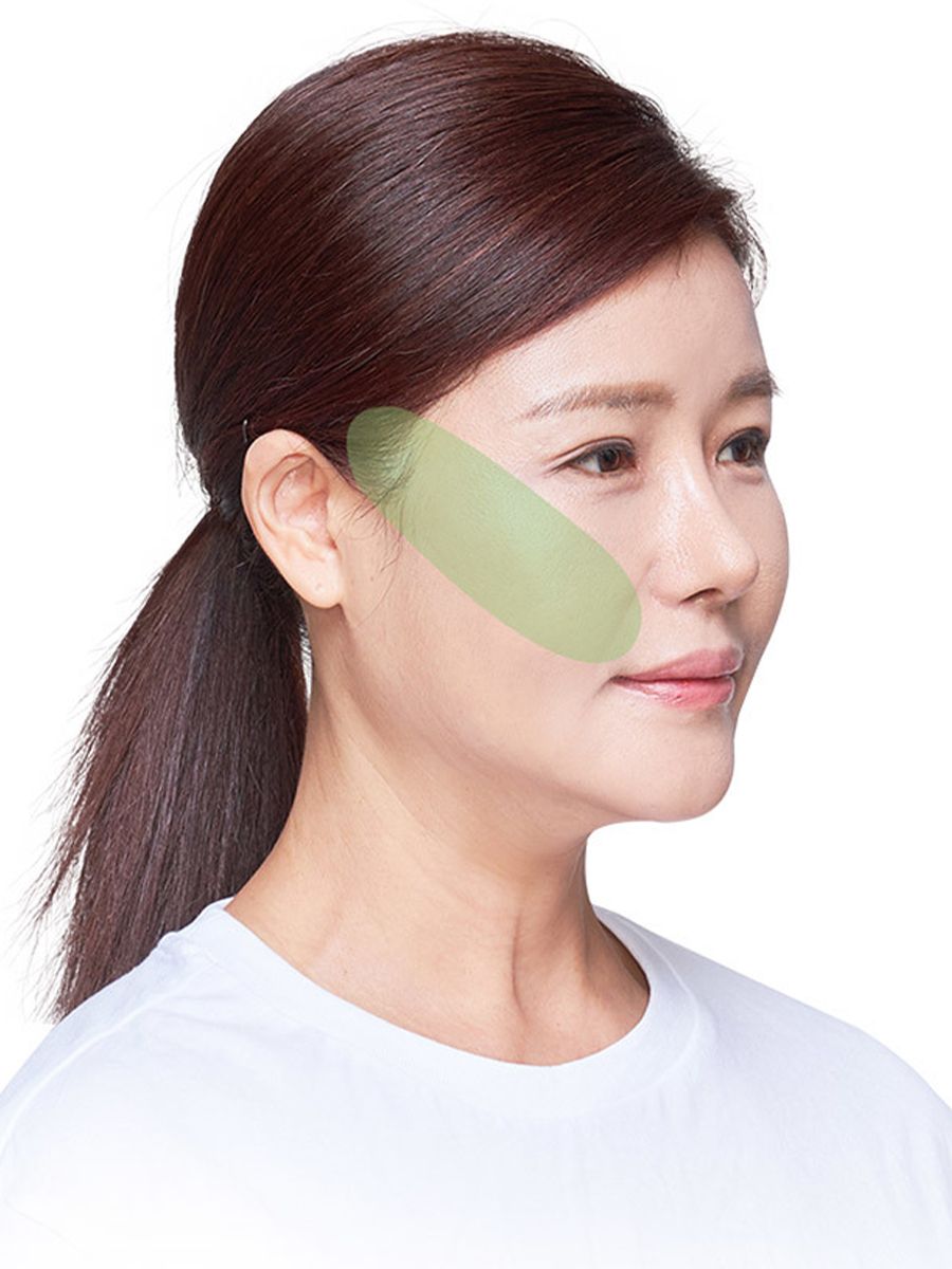 Woman with a green highlighted area on her cheek and jawline. She has dark hair in a ponytail.