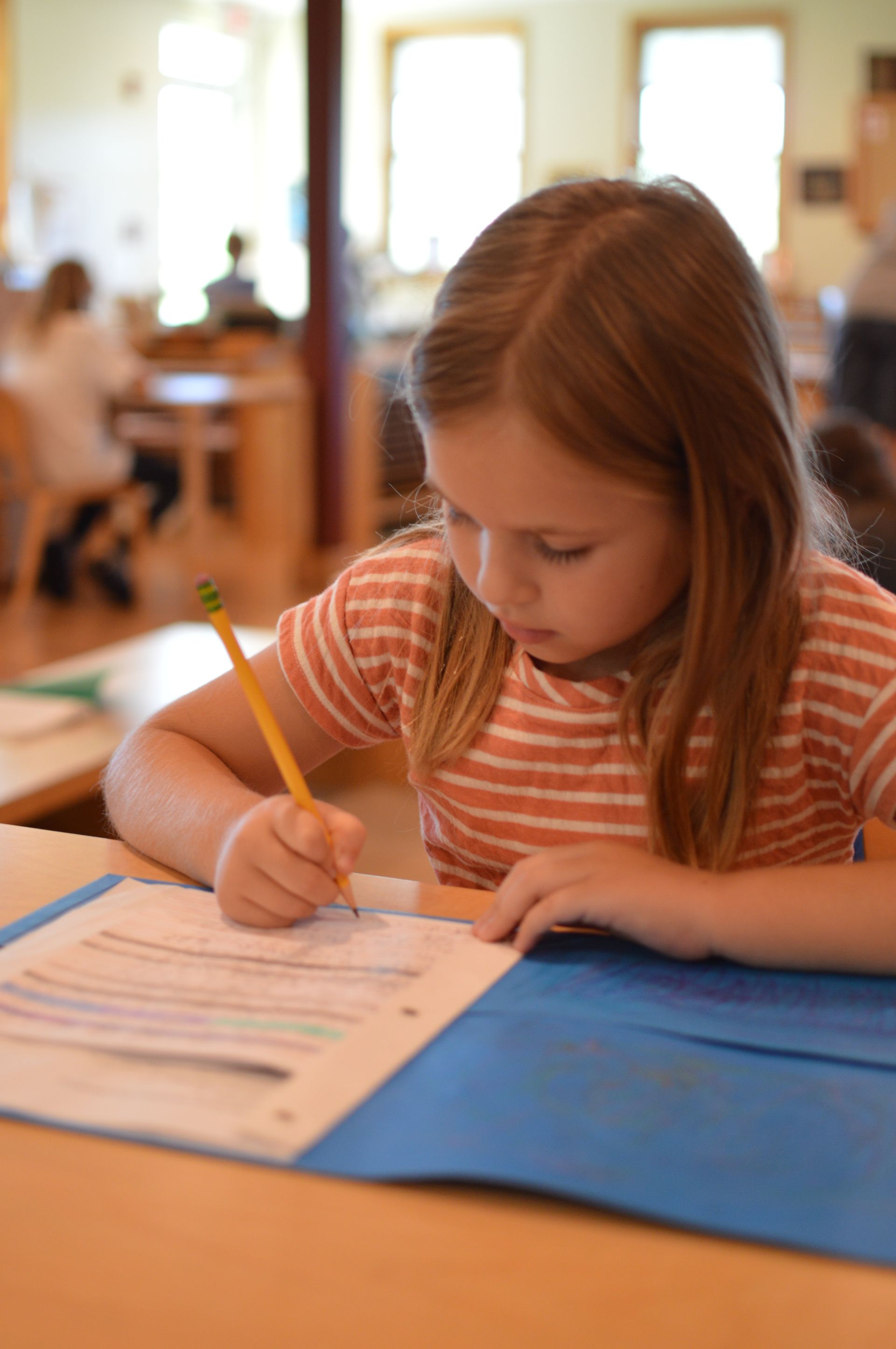 A Montessori Elementary child writing on paper