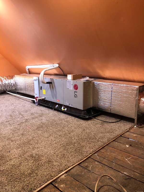 LG HVAC unit in an attic, with ductwork and insulation on a carpeted floor.