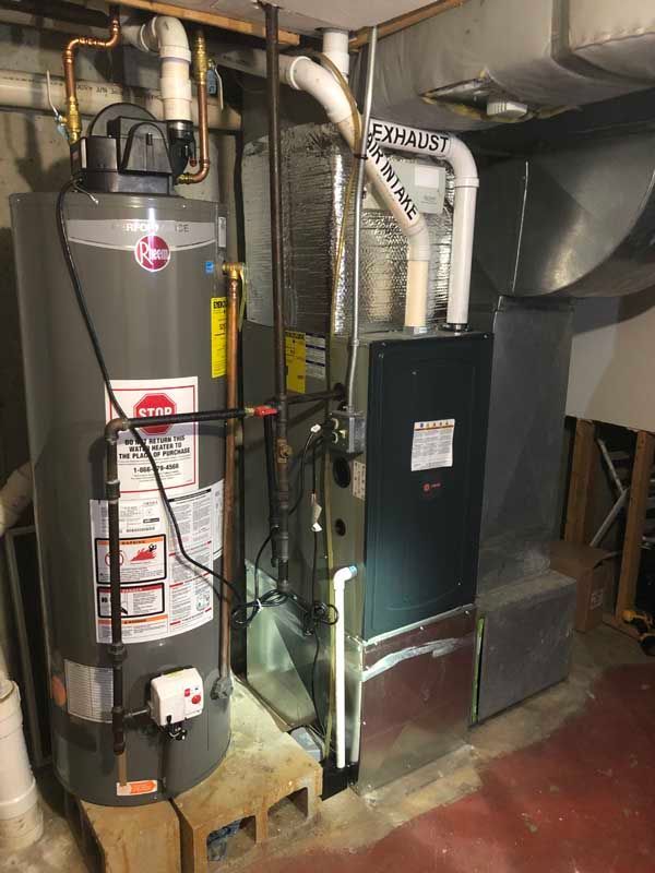 A basement with a water heater, furnace, and ductwork, all in a room with concrete blocks and red flooring.