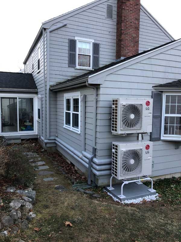 Gray house exterior with two outdoor AC units. Windows, chimney, and yard are visible.