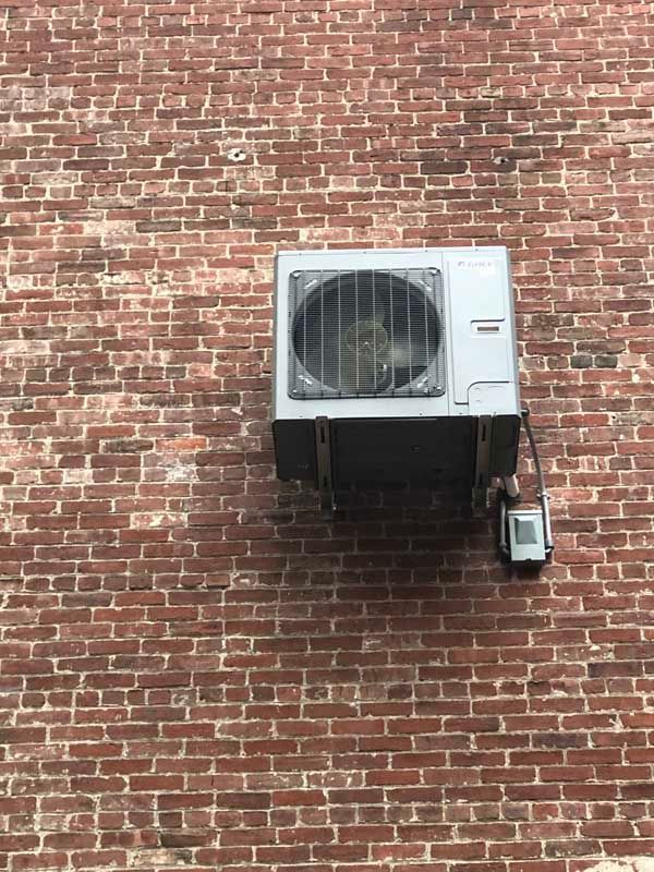 Air conditioning unit mounted on a red brick wall.