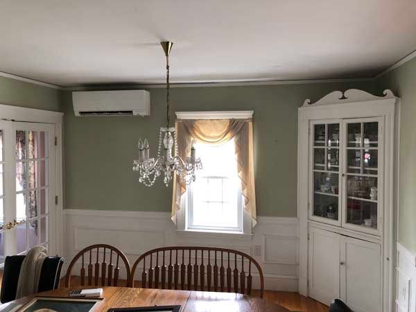 Dining room with green walls, white trim, and a chandelier.