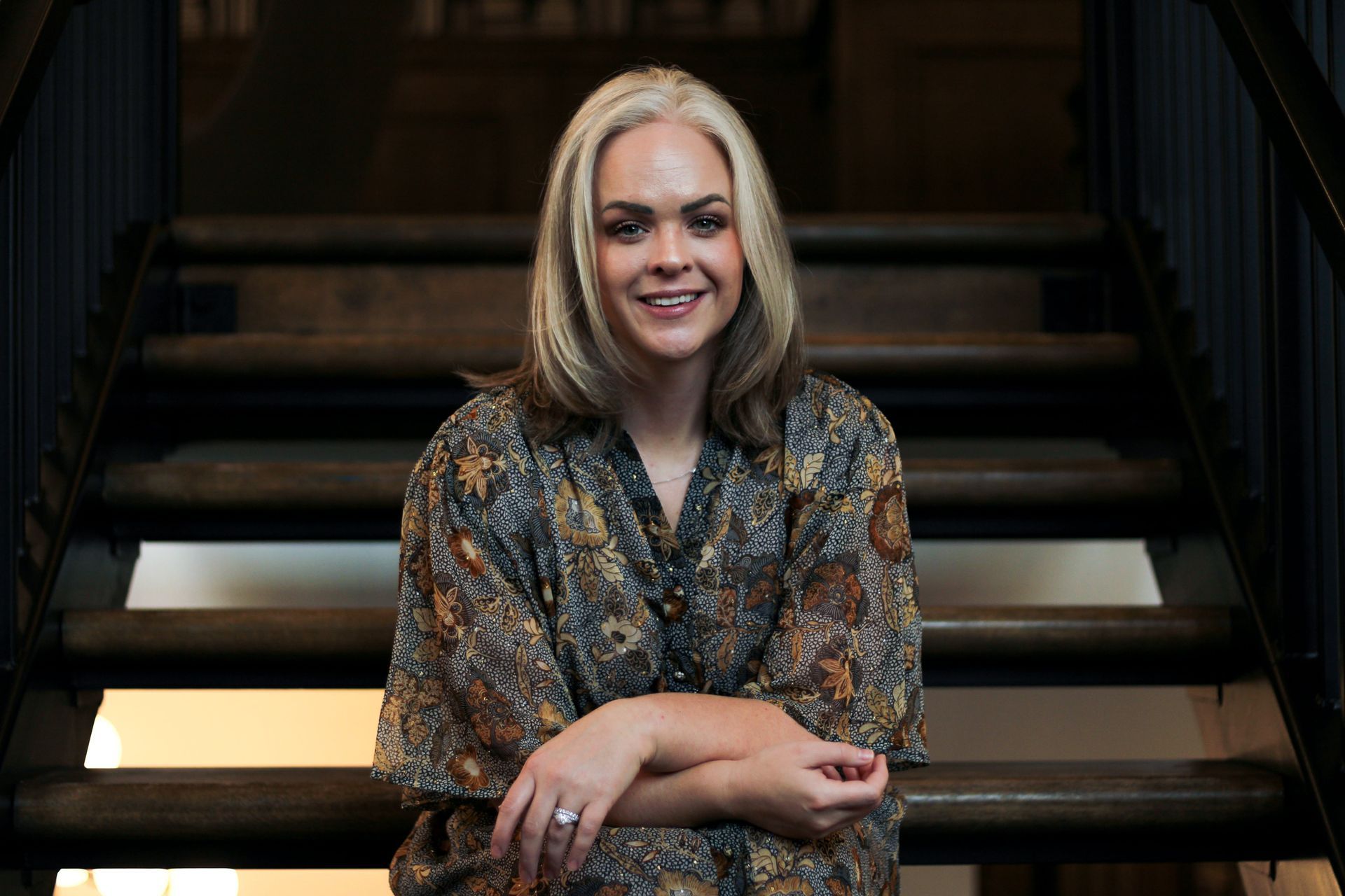 A woman is sitting on a set of stairs smiling.