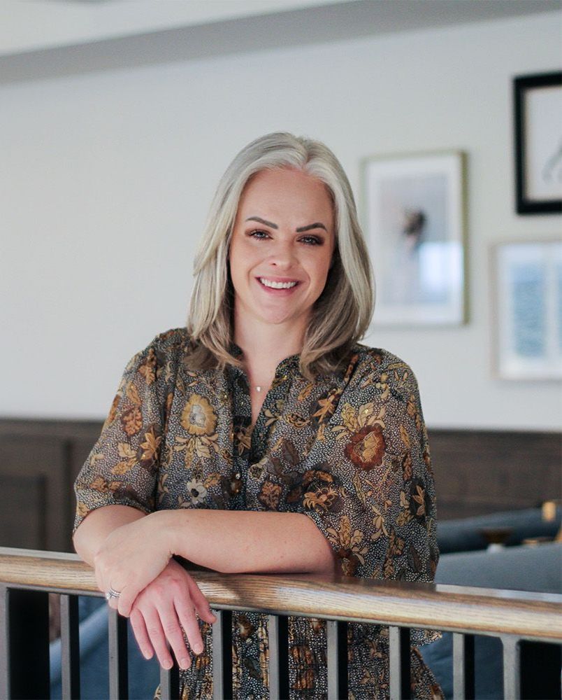 A woman is leaning on a railing and smiling.