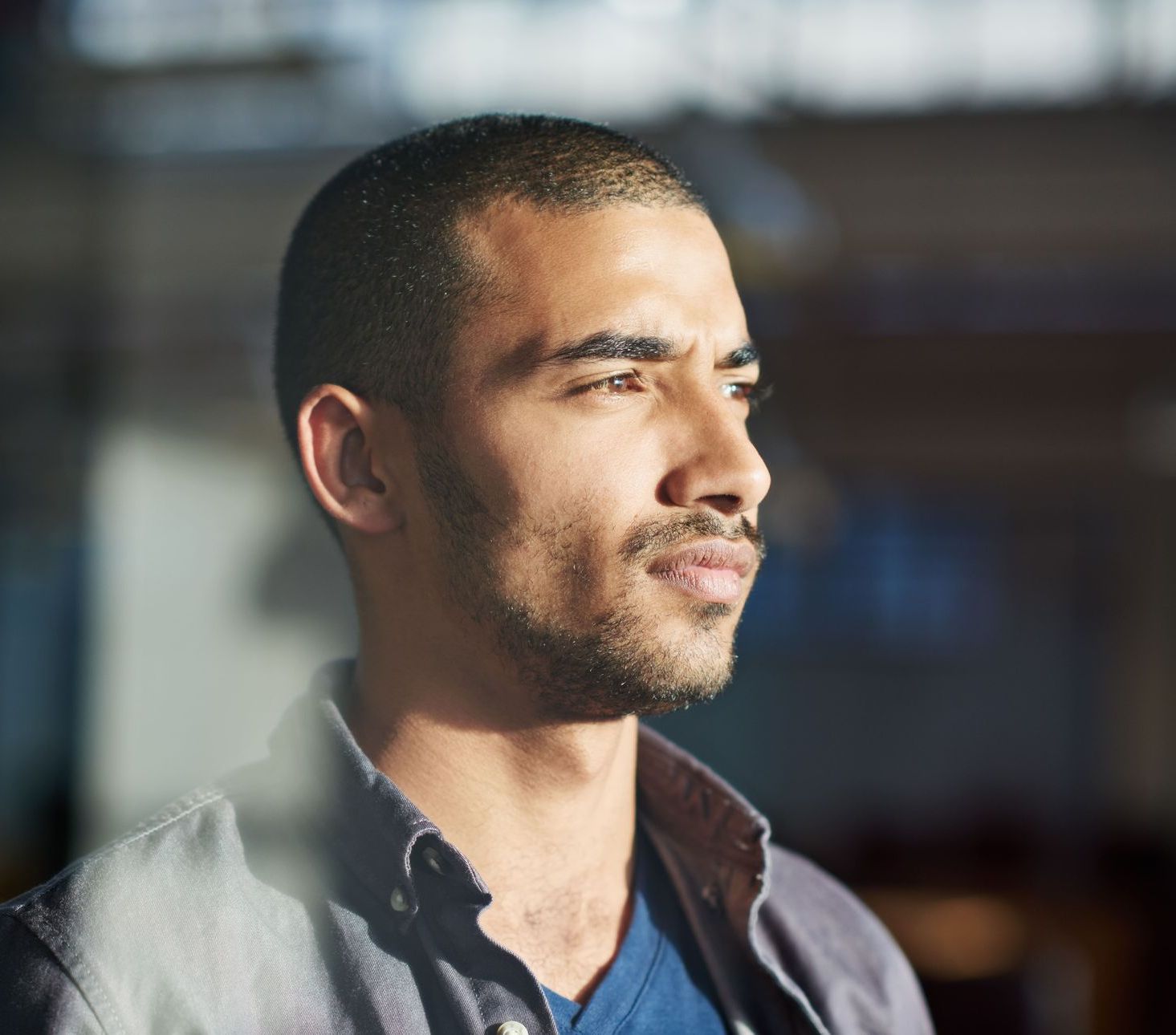 A man with a beard is looking out a window