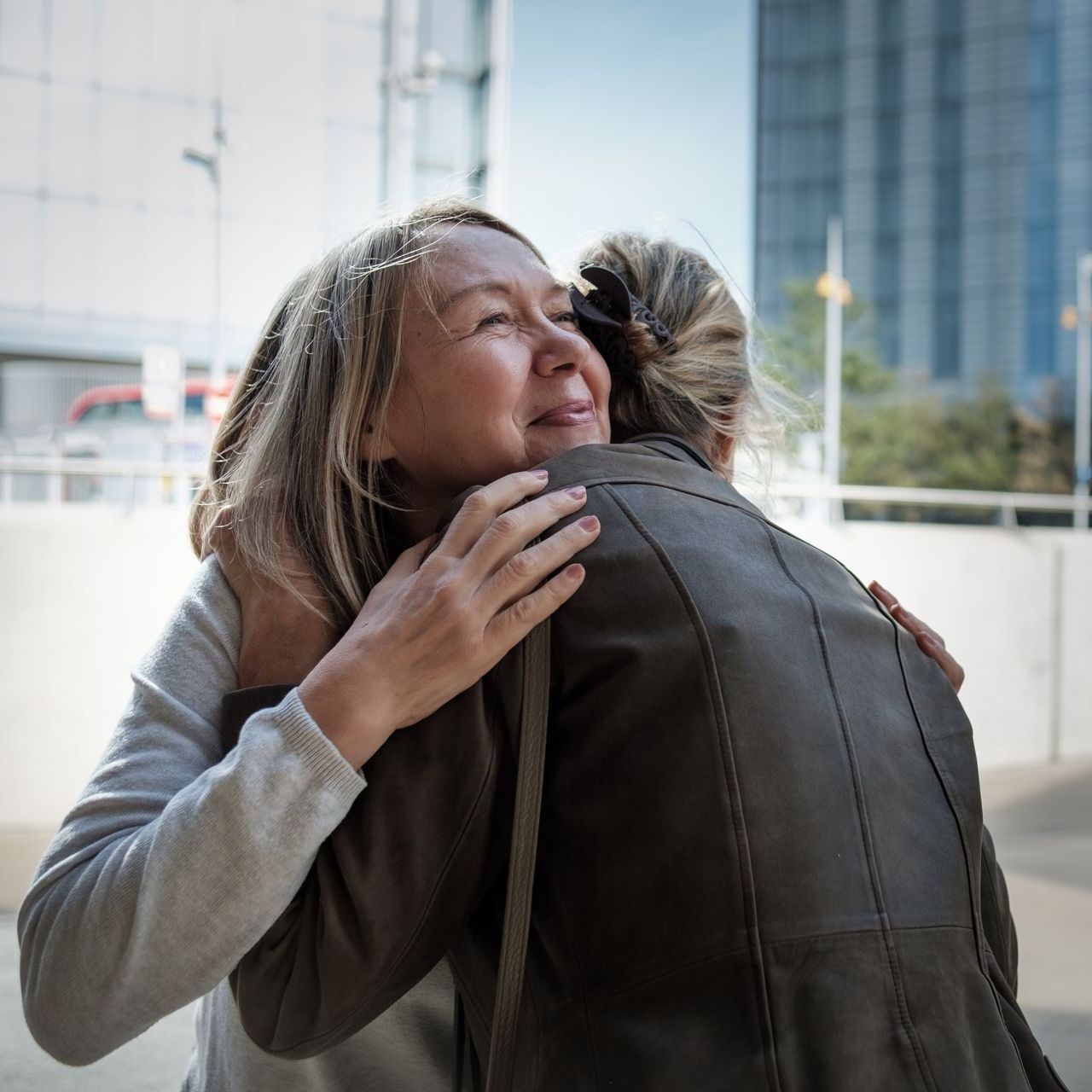 A woman in a leather jacket is hugging another woman