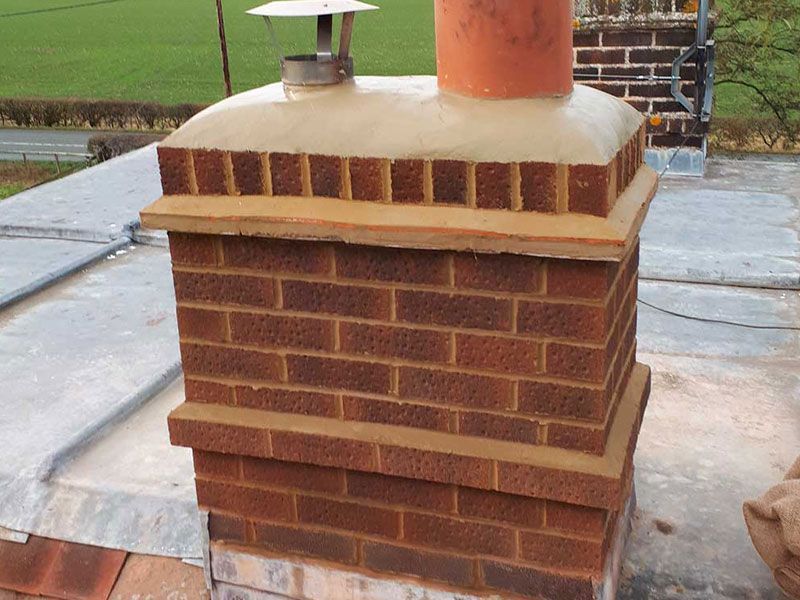 A brick chimney is sitting on top of a roof