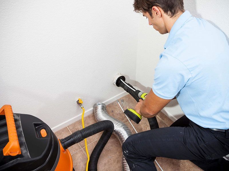 A man is cleaning a duct with a vacuum cleaner.