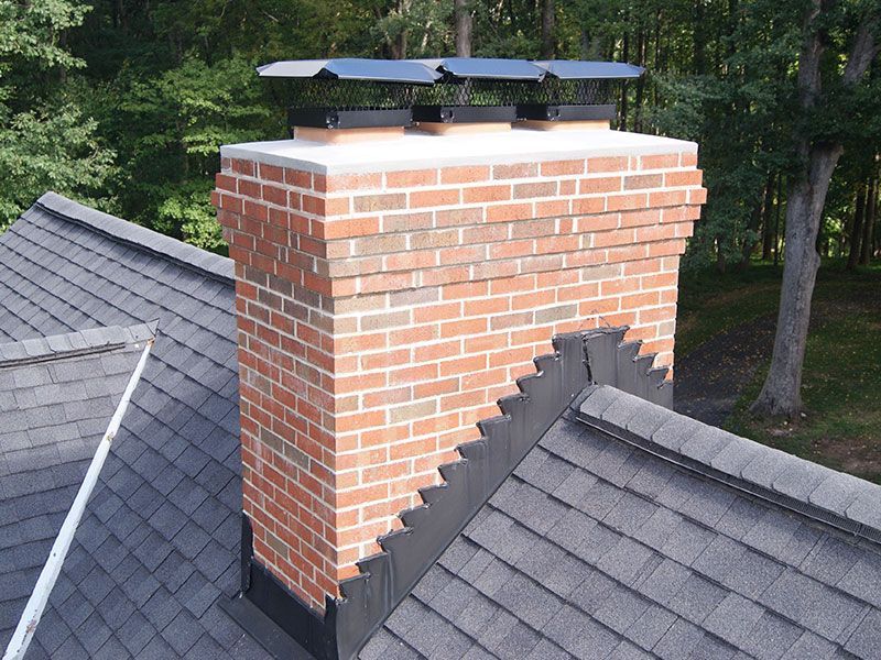 A man is standing on a roof next to a chimney