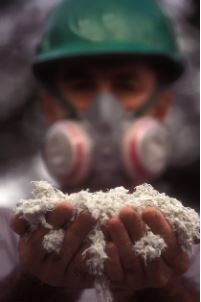 This is a technician in full protective equipment demonstrating the fluffiness of vermiculite insulation.