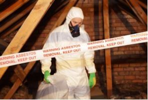This is an abatement technician in a cornered off area working to remove asbestos.
