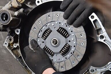 Man holding a silver metal vehicle clutch — Transmission Grinding Gears in Collingswood, NJ