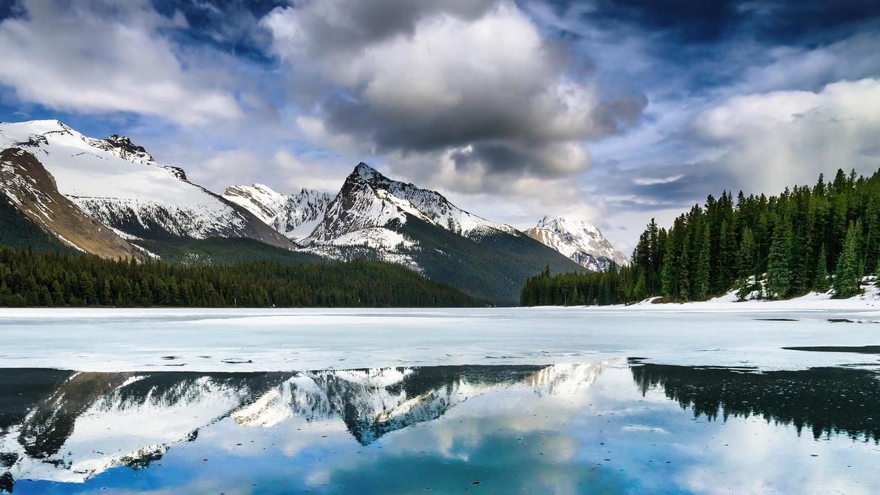 A lake surrounded by snow covered mountains and trees