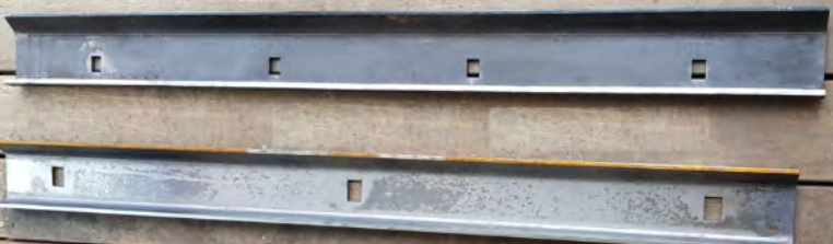 Two Metal Tracks With Square Cutouts Lie on a Wood Surface — Northern Heavy Machinery in Mount Louisa, QLD