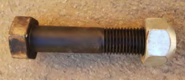 A Bolt With a Nut Screwed Onto It, Resting on a Textured Brown Surface — Northern Heavy Machinery in Mount Louisa, QLD