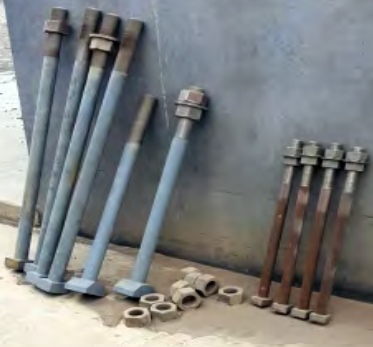 Long Metal Bolts and Nuts Leaning Against a Gray Wall — Northern Heavy Machinery in Mount Louisa, QLD