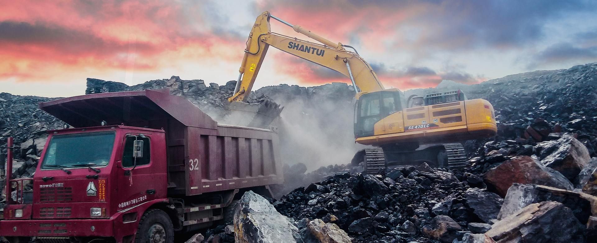 Yellow Excavator Loading Dark Material Into a Red Dump Truck — Northern Heavy Machinery in Mount Louisa, QLD