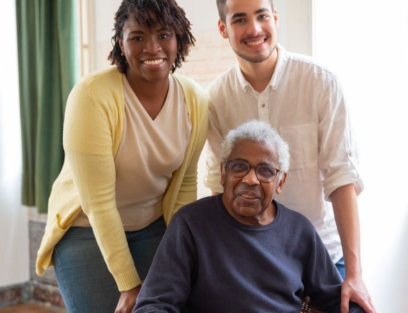 A group of people are posing for a picture with an elderly woman in a wheelchair.