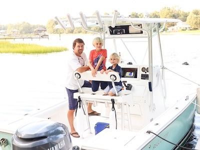 A man and two children are standing on a boat.